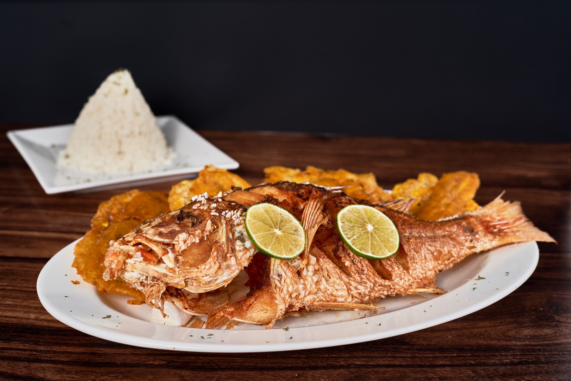 Whole fried fish served with rice and plantains